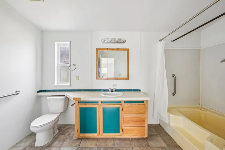 Bathroom featuring a single vanity with storage, a medicine cabinet, and a built-in bathtub with shower curtain rod