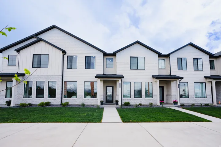 Contemporary exterior with white siding and dark trim, featuring a stone veneer accent