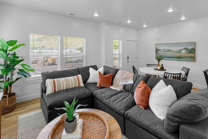 Open-concept living area featuring wood-finish flooring, white walls, recessed lighting, and multiple windows with blinds