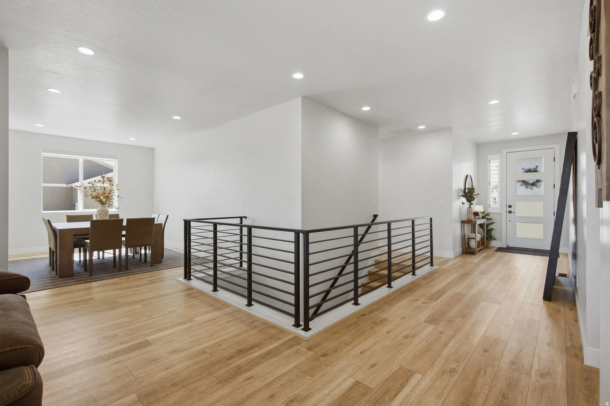 LVP wood-finish flooring, recessed lighting, and a contemporary black metal railing.