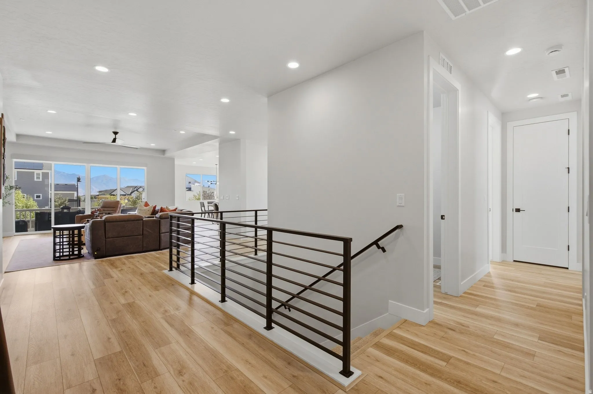 LVP flooring throughout, modern horizontal metal stair railing, recessed lighting, and expansive windows.