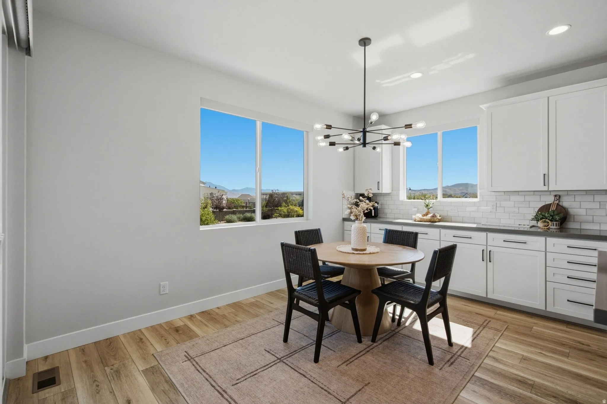 White cabinetry with dark hardware, subway tile backsplash, dark countertops, and LVP wood-finish flooring.