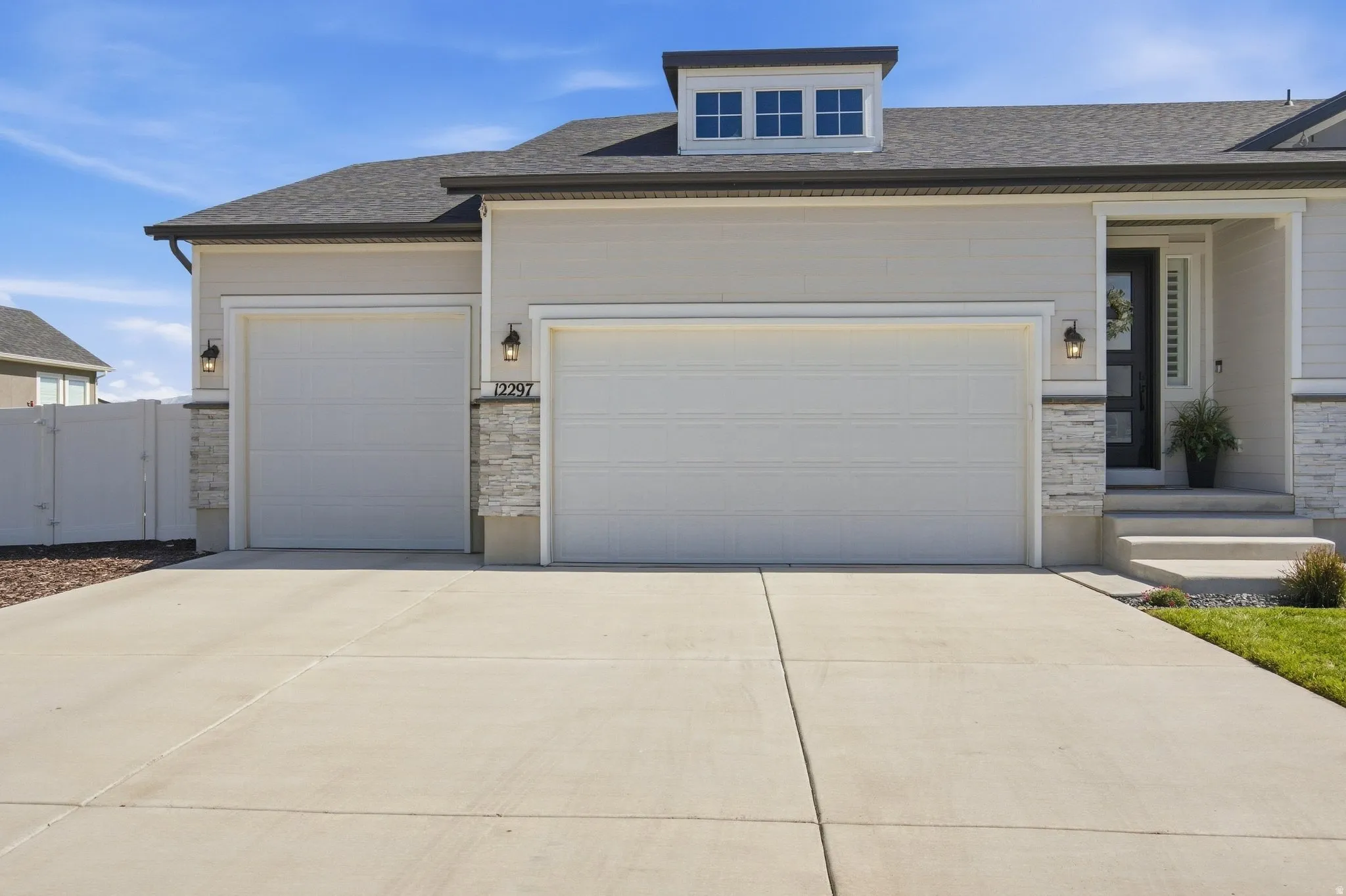 Attached 4-car garage, tandem deep, stone veneer accents, concrete driveway.