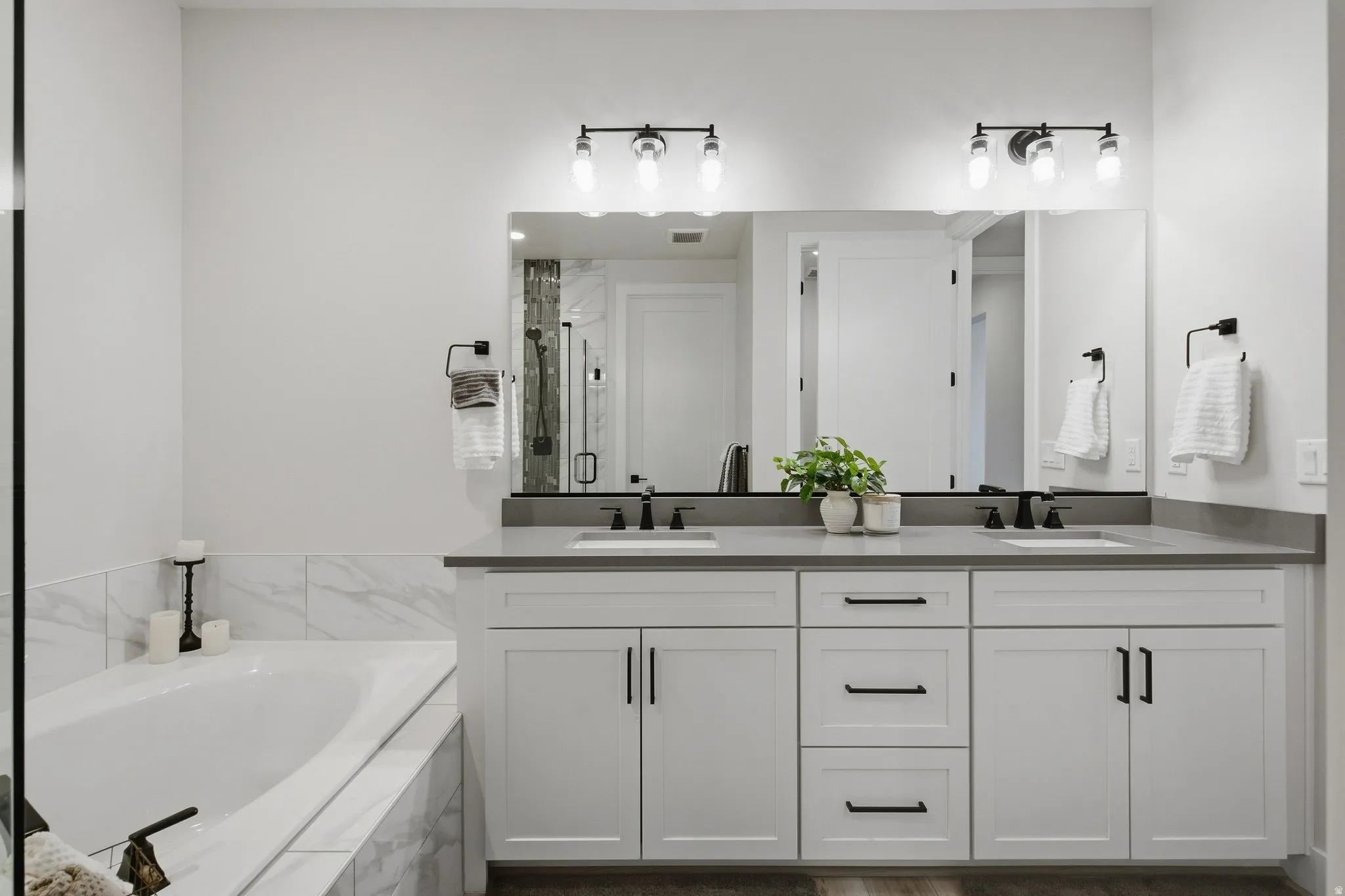 Primary en-suite with dual vanity, gray countertop, and matte black fixtures.