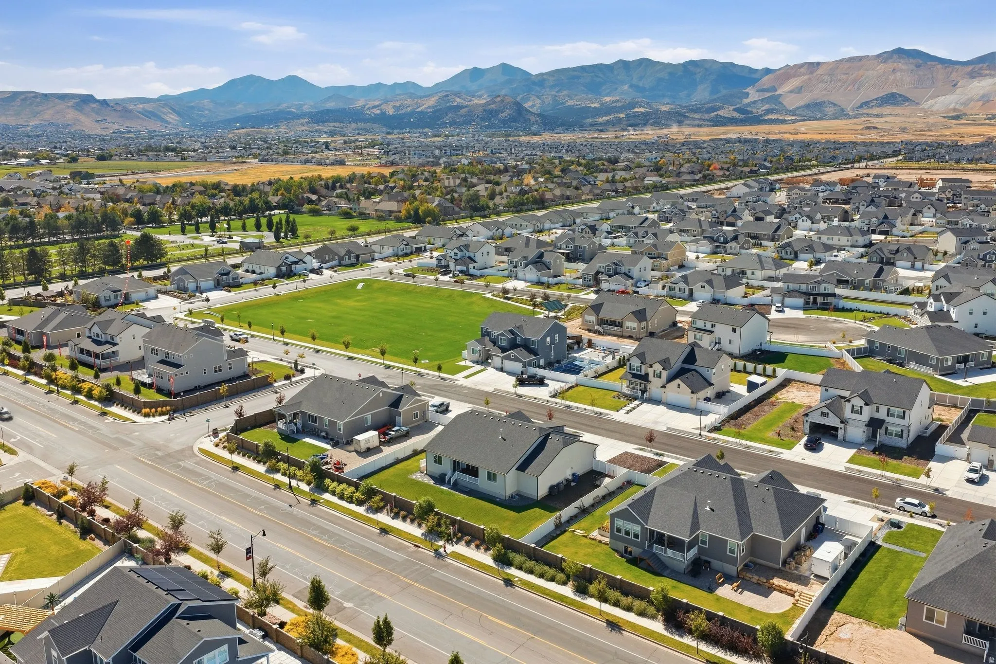 Expansive community with a manicured green space, surrounded by residential properties, and a prominent mountain range in the background