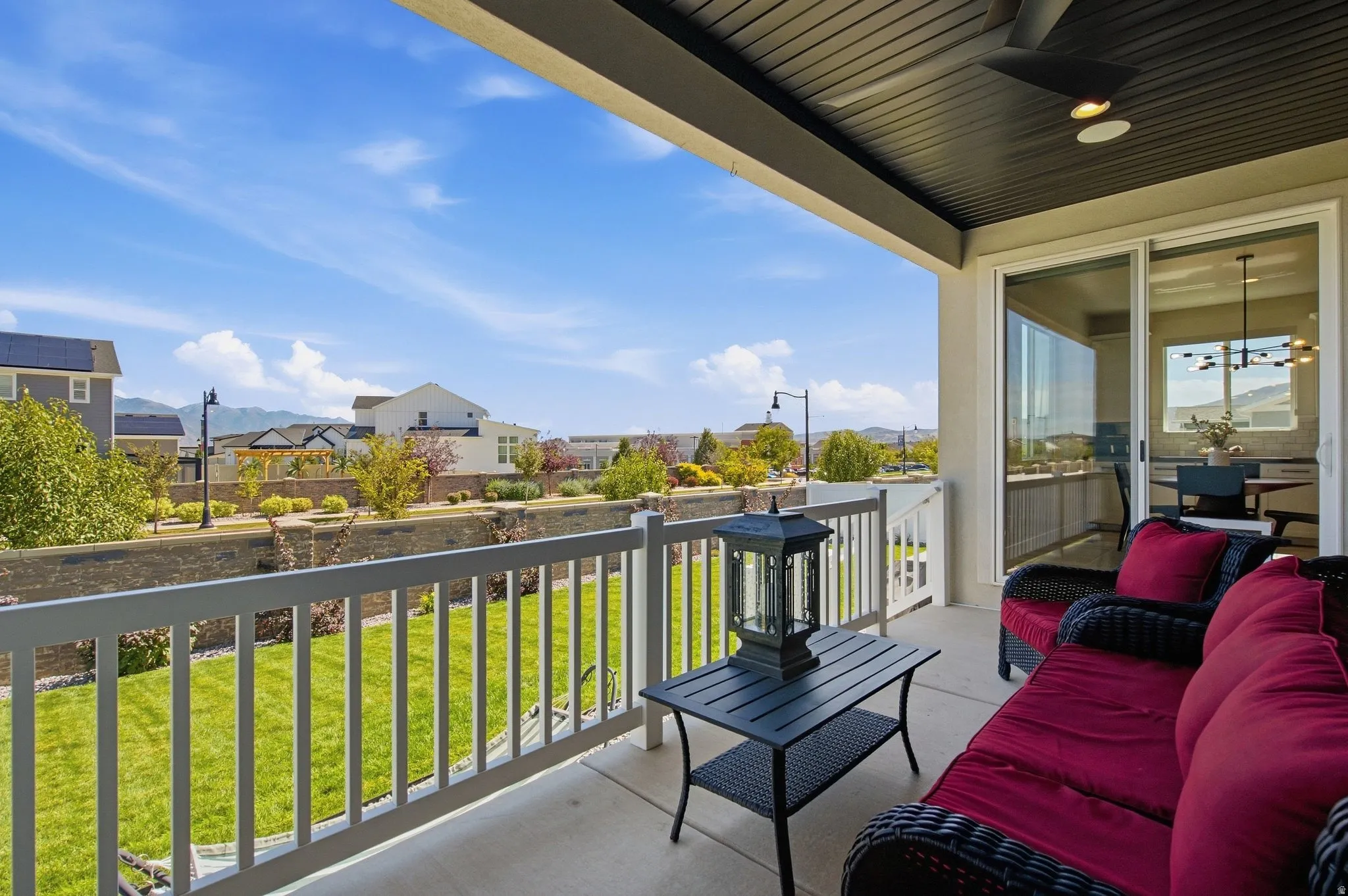 Covered outdoor patio with concrete flooring, white railings, and a black ceiling fan.