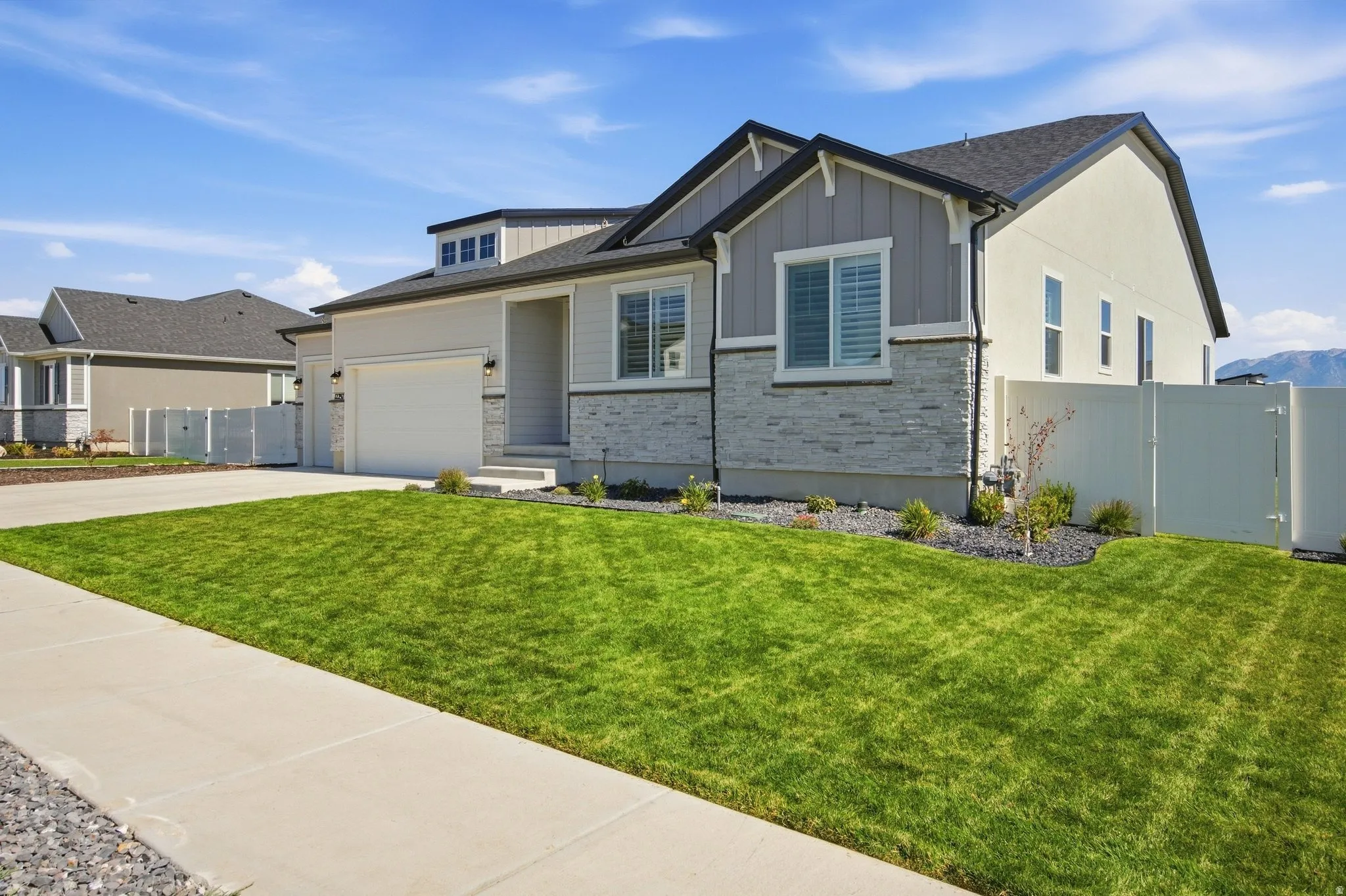 Rambler exterior with a 4-car garage, stone veneer accents, and a dark asphalt shingle roof.