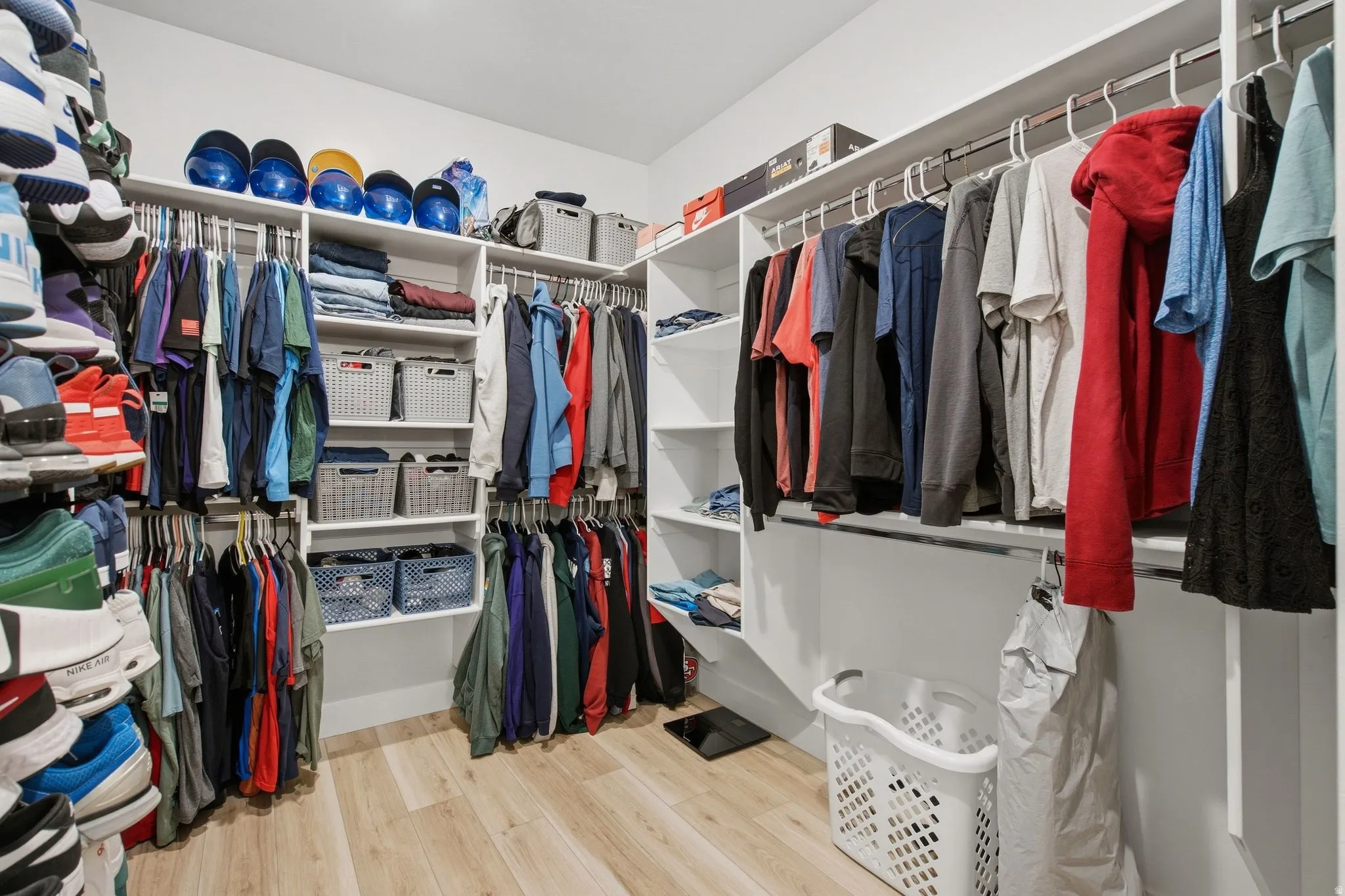 Primary walk in closet with multiple shelving units, hanging rods, and LVP wood-finish flooring.