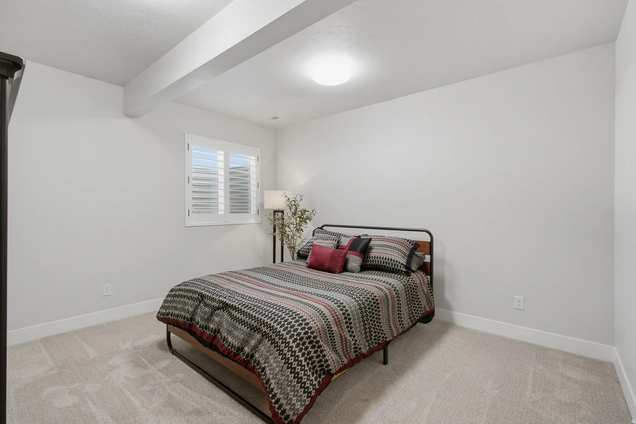 Carpeted flooring, window with shutters, recessed lighting, neutral white walls.