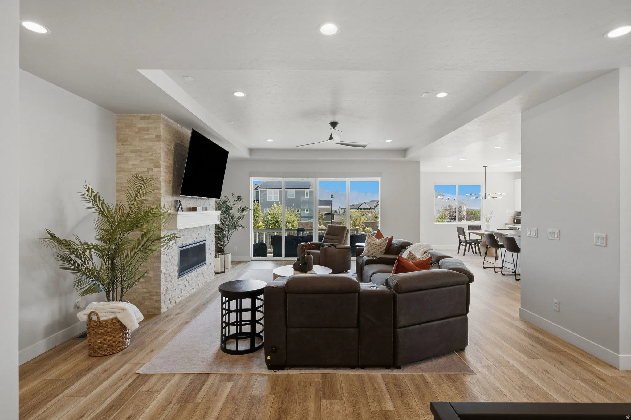 Open-concept living space featuring LVP flooring, a stacked stone fireplace with a white mantel, and recessed lighting.