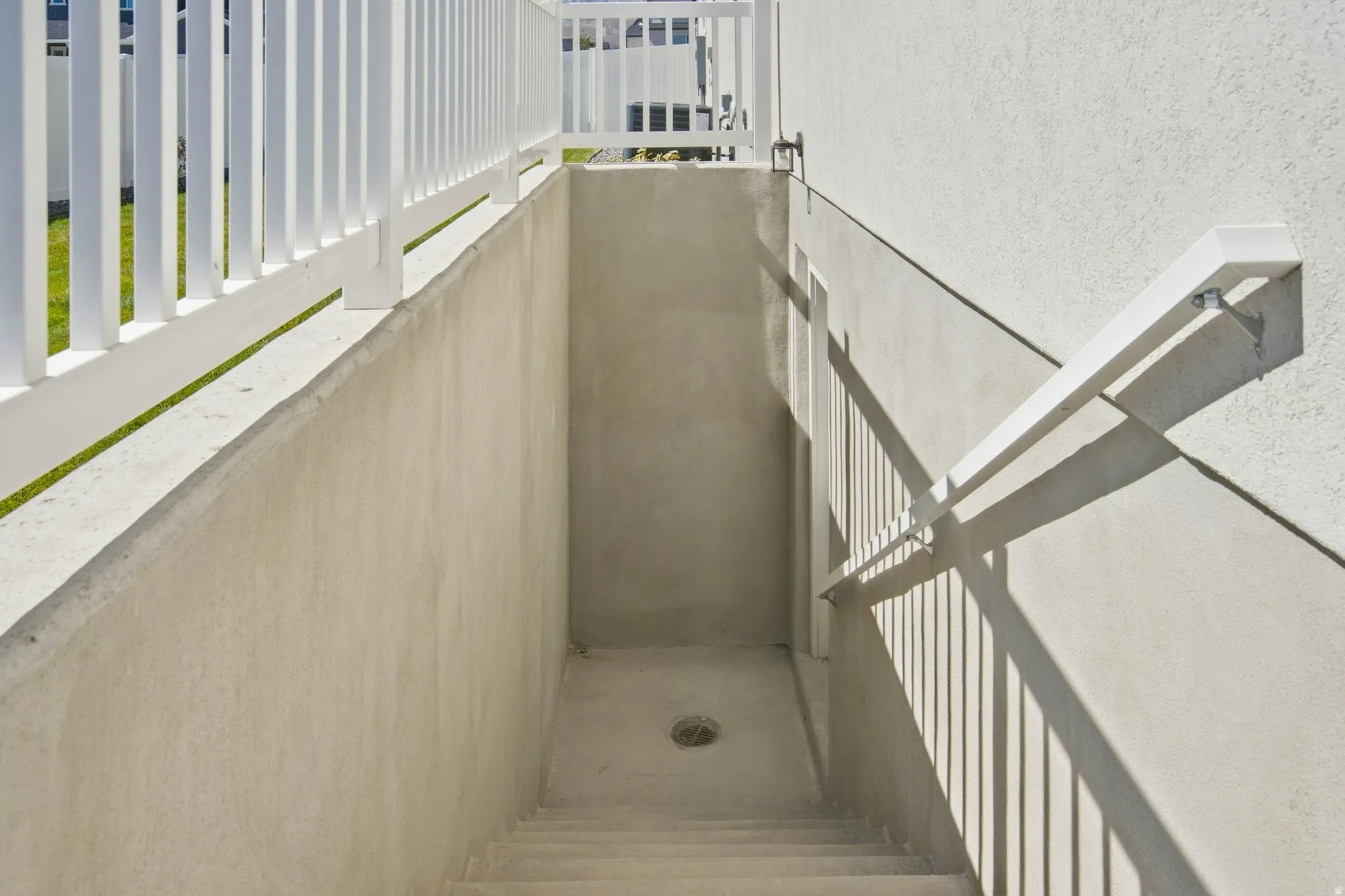 Separate basement entrance, with a concrete stairway with white handrails.