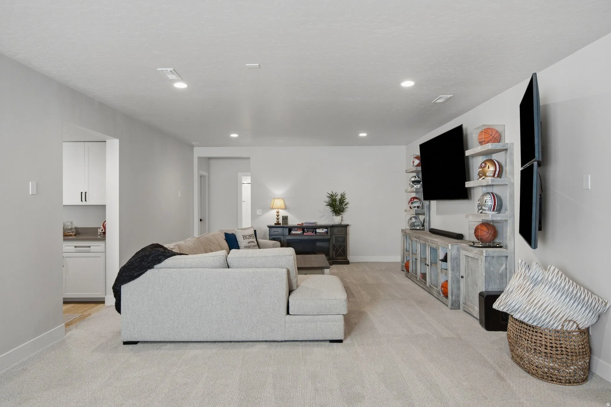 Recessed lighting illuminates a spacious family room area featuring plush carpeting.