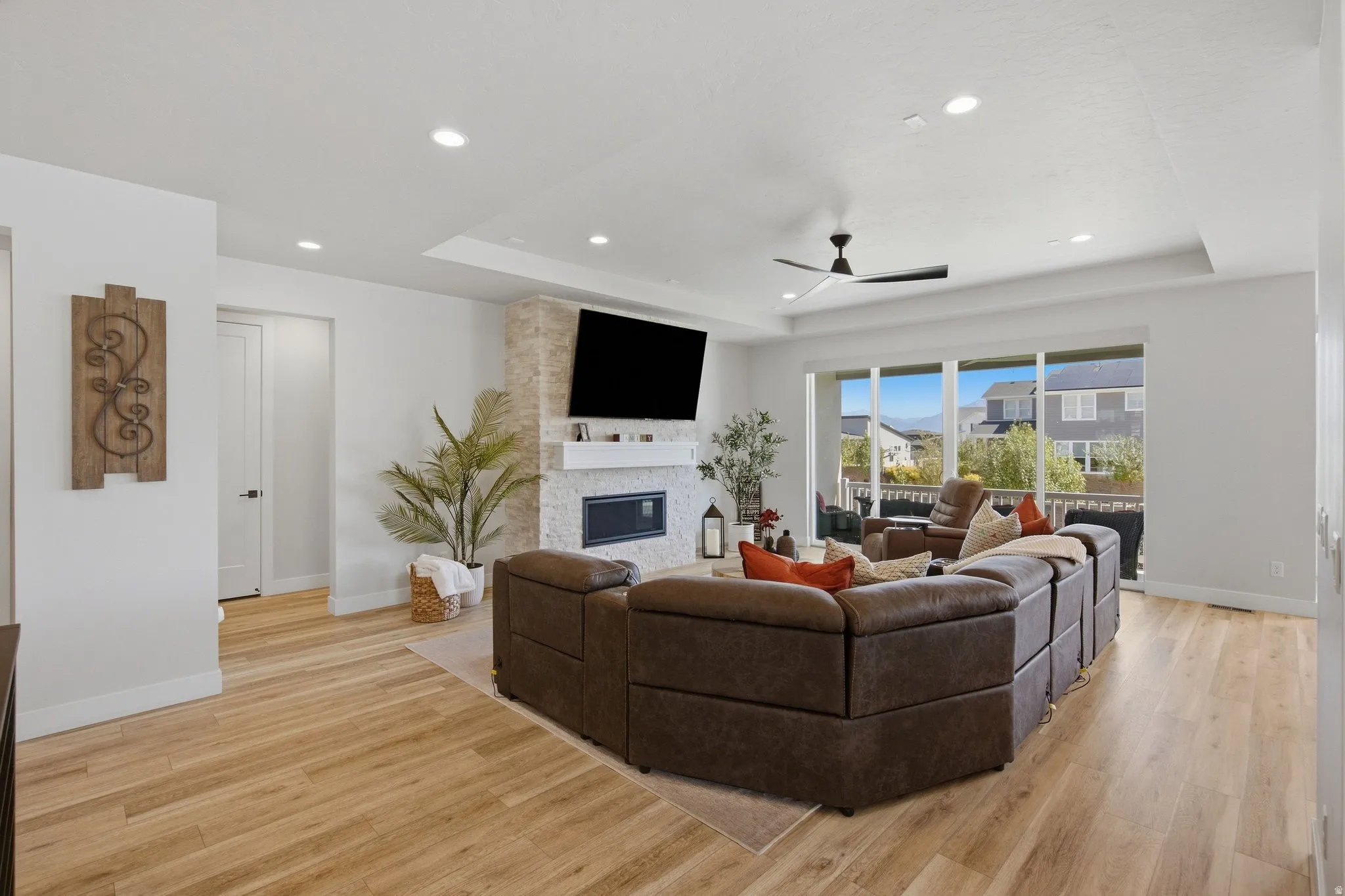 Spacious living area featuring LVP flooring, a contemporary ceiling fan, and recessed lighting.