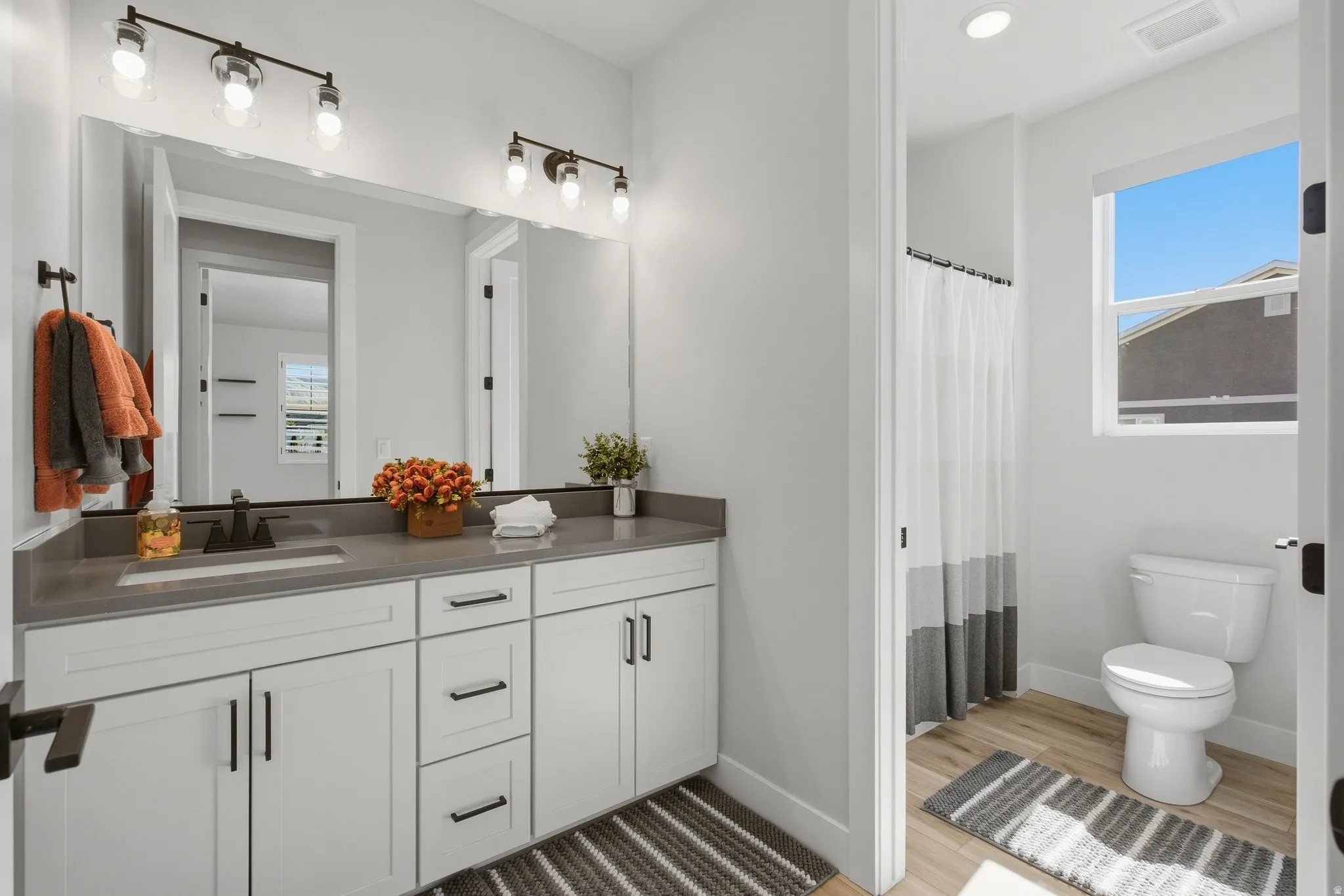 White vanity cabinetry, dark hardware, and a grey countertop.