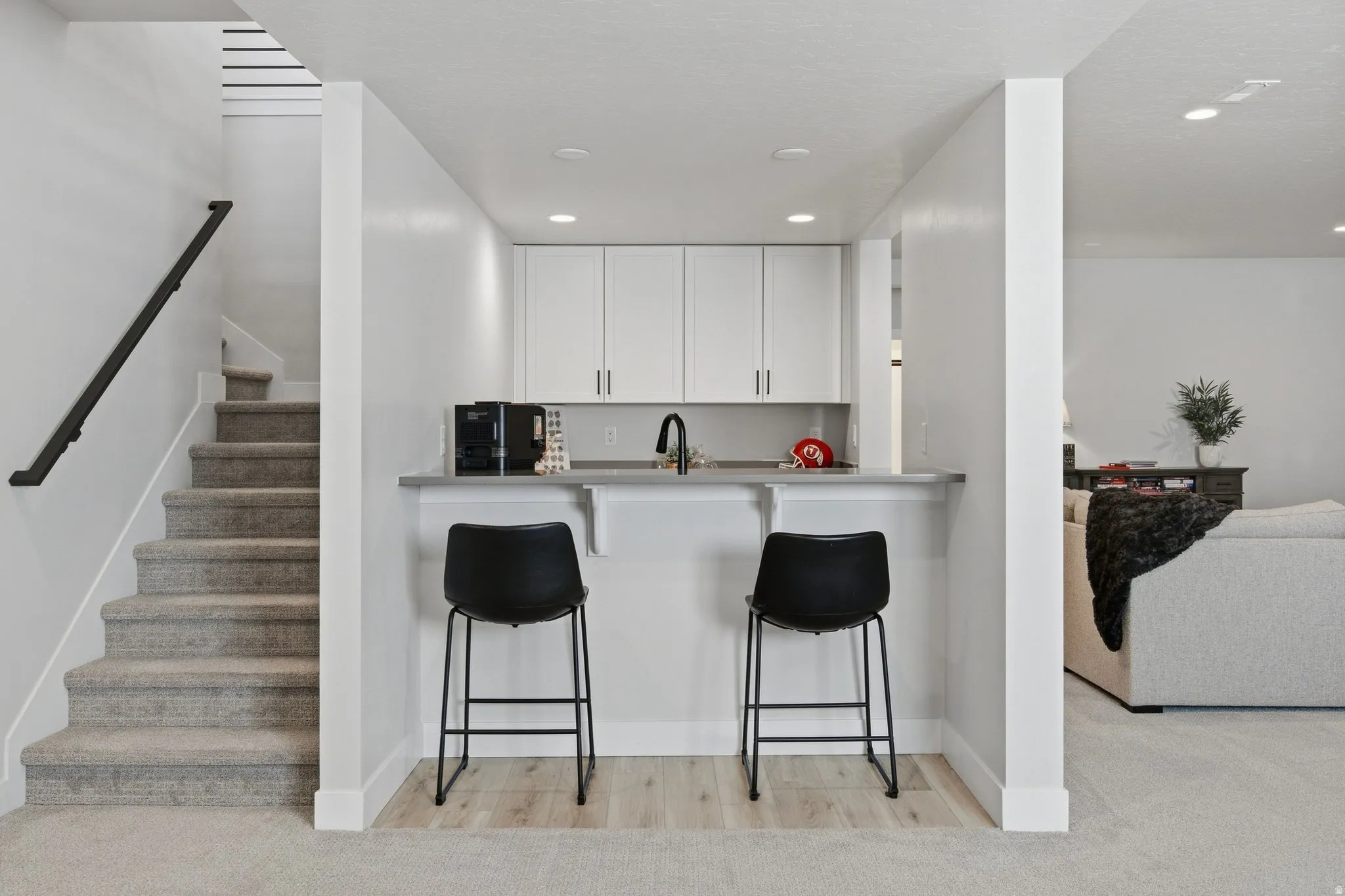 Built-in wet bar with white cabinetry, sink, and counter seating, connects to the family room.