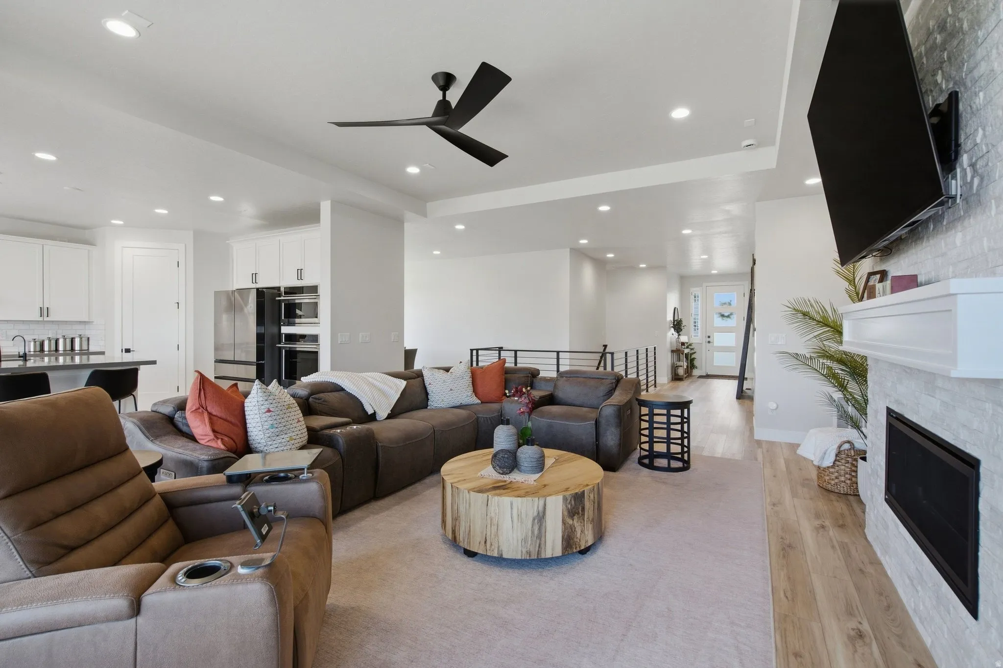Open-concept living area with a stone-clad fireplace and LVP flooring.