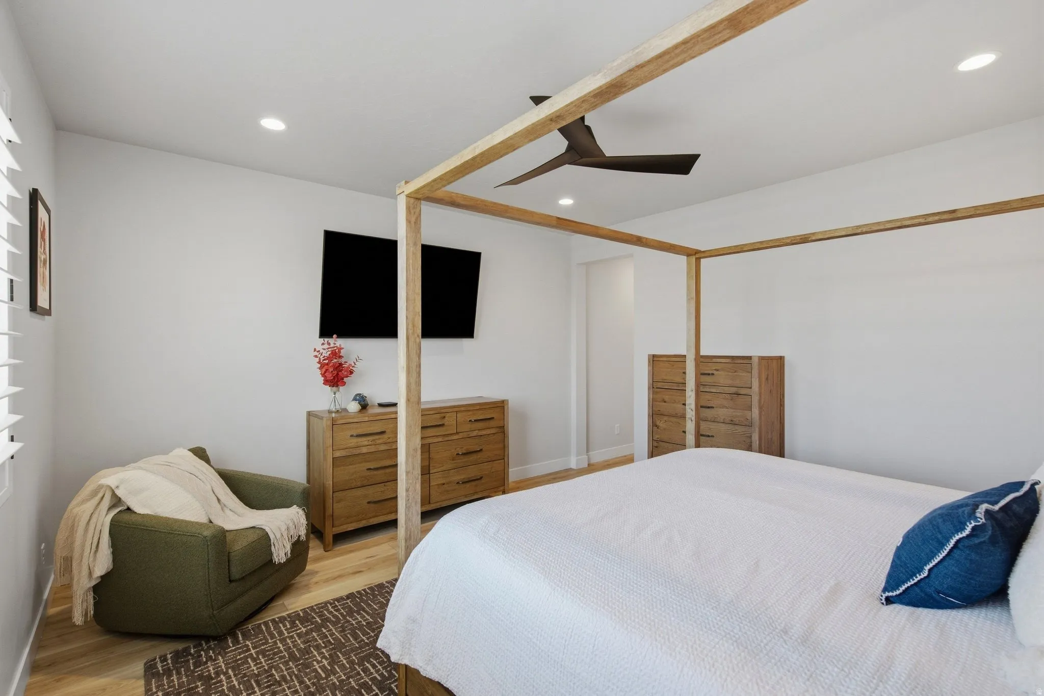 Primary bedroom with recessed lighting, ceiling fan, LVP wood-finish flooring, white walls.