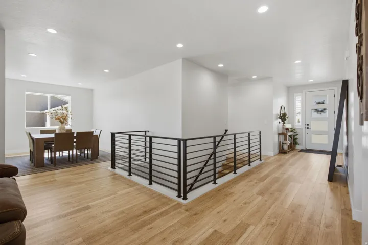 LVP wood-finish flooring, recessed lighting, and a contemporary black metal railing.