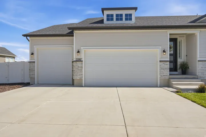 Attached 4-car garage, tandem deep, stone veneer accents, concrete driveway.