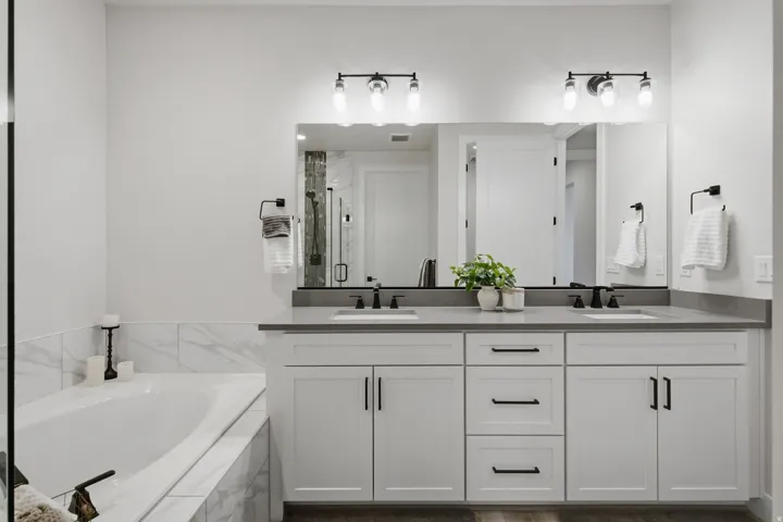 Primary en-suite with dual vanity, gray countertop, and matte black fixtures.