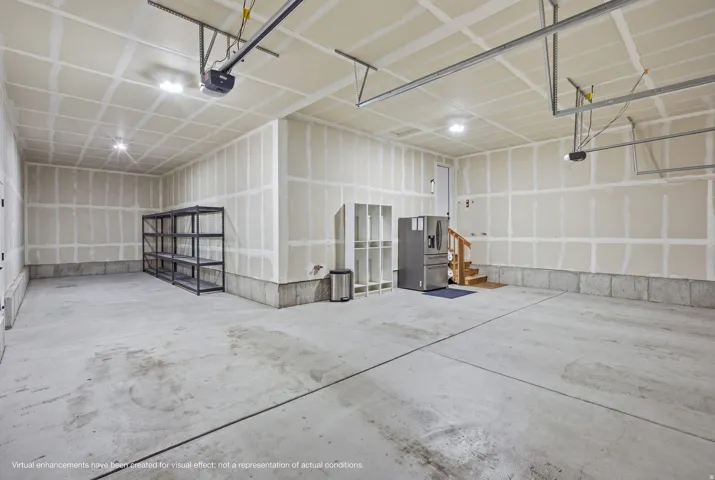 Spacious tandem, 4 car-garage, with concrete flooring, and built-in overhead lighting.