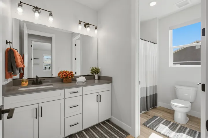 White vanity cabinetry, dark hardware, and a grey countertop.