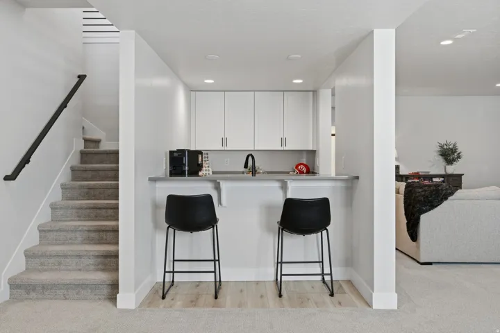 Built-in wet bar with white cabinetry, sink, and counter seating, connects to the family room.