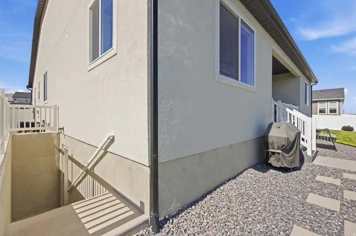 Stucco exterior with stairwell, leading to separate basement entrance.
