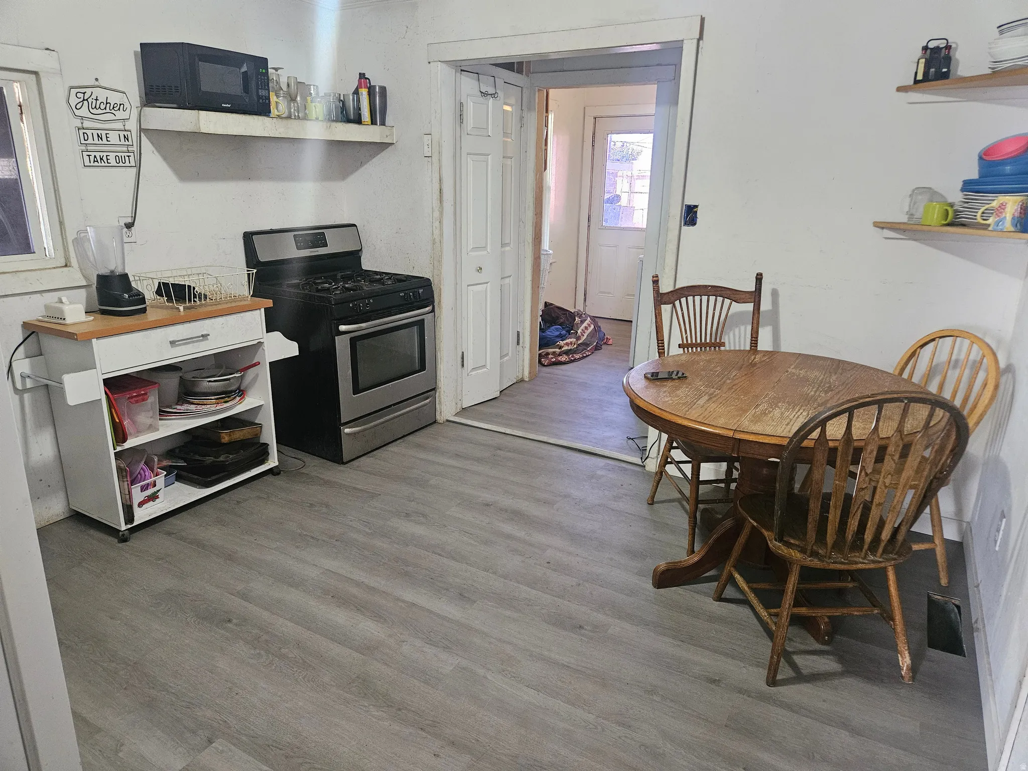 Stainless steel gas range, open shelving, and wood-finish flooring
