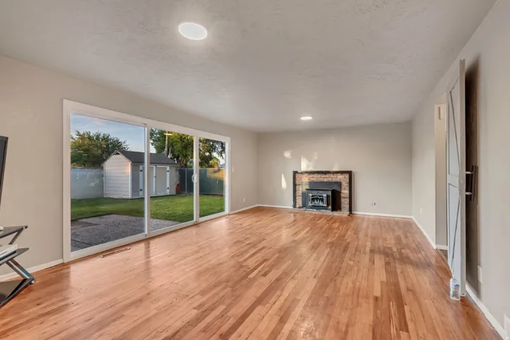 Hardwood flooring, sliding glass door, recessed lighting, brick-surround fireplace, and a barn-style interior door