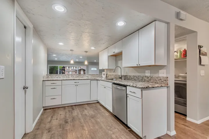 Kitchen featuring wood-finish flooring, white cabinetry, integrated stainless steel appliances, and recessed ceiling lighting