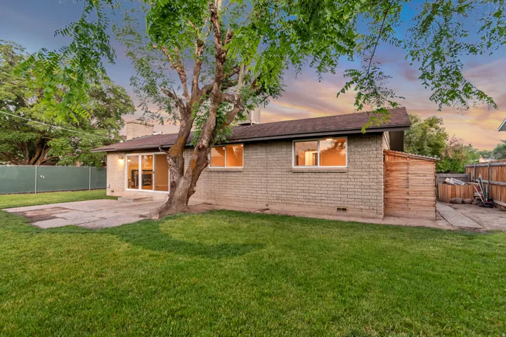 Expansive grassy yard with mature tree, concrete patio, and brick exterior