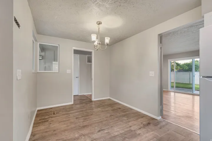 Wood-finish flooring with a brushed nickel chandelier, light gray painted walls, and white trim