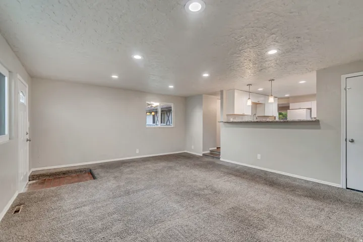 Open-concept living space featuring recessed lighting, a pass-through counter, and pendant lighting
