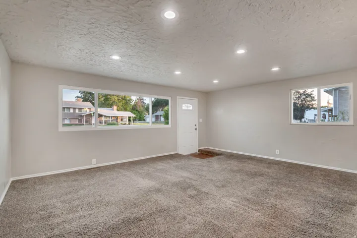 Recessed lighting, neutral wall paint, white trim, gray carpet flooring, and multiple windows
