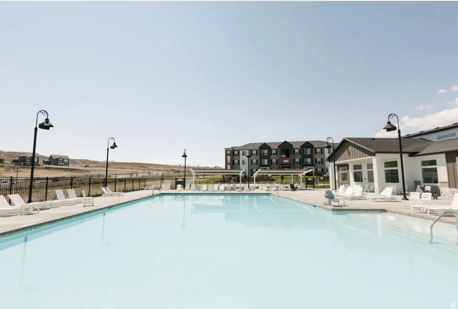 Expansive outdoor pool with integrated steps, surrounded by a concrete deck and multiple lounge chairs