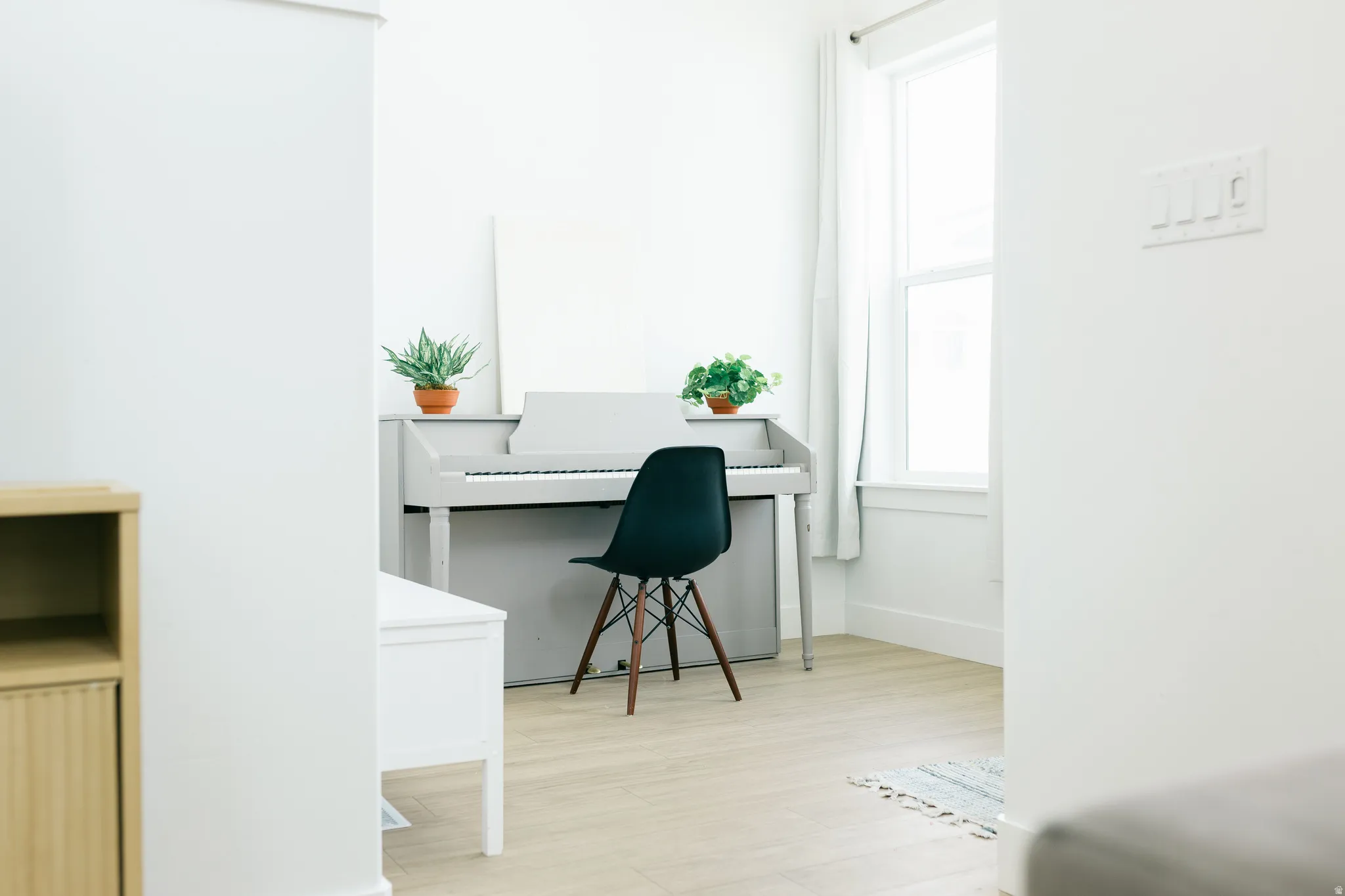 Light wood-finish flooring, white walls, and a large window with white trim