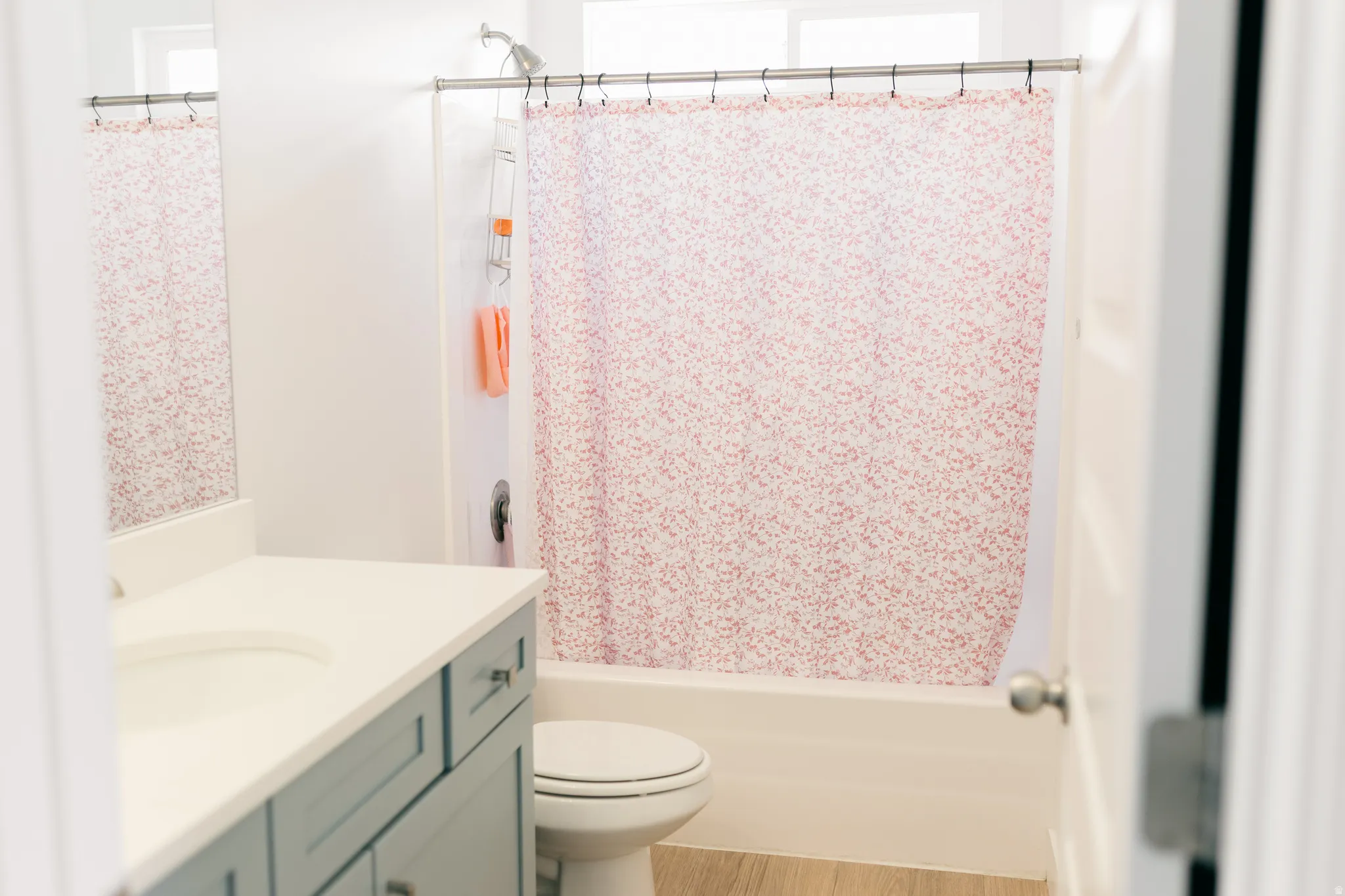Bathroom featuring a single vanity with light countertop, white toilet, and a shower/tub combination with a chrome fixture
