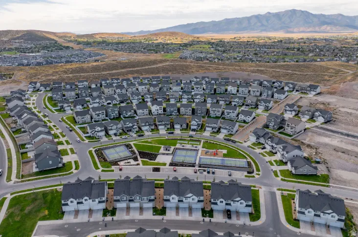 Expansive community featuring multiple residential structures, central green spaces, and dedicated recreational courts