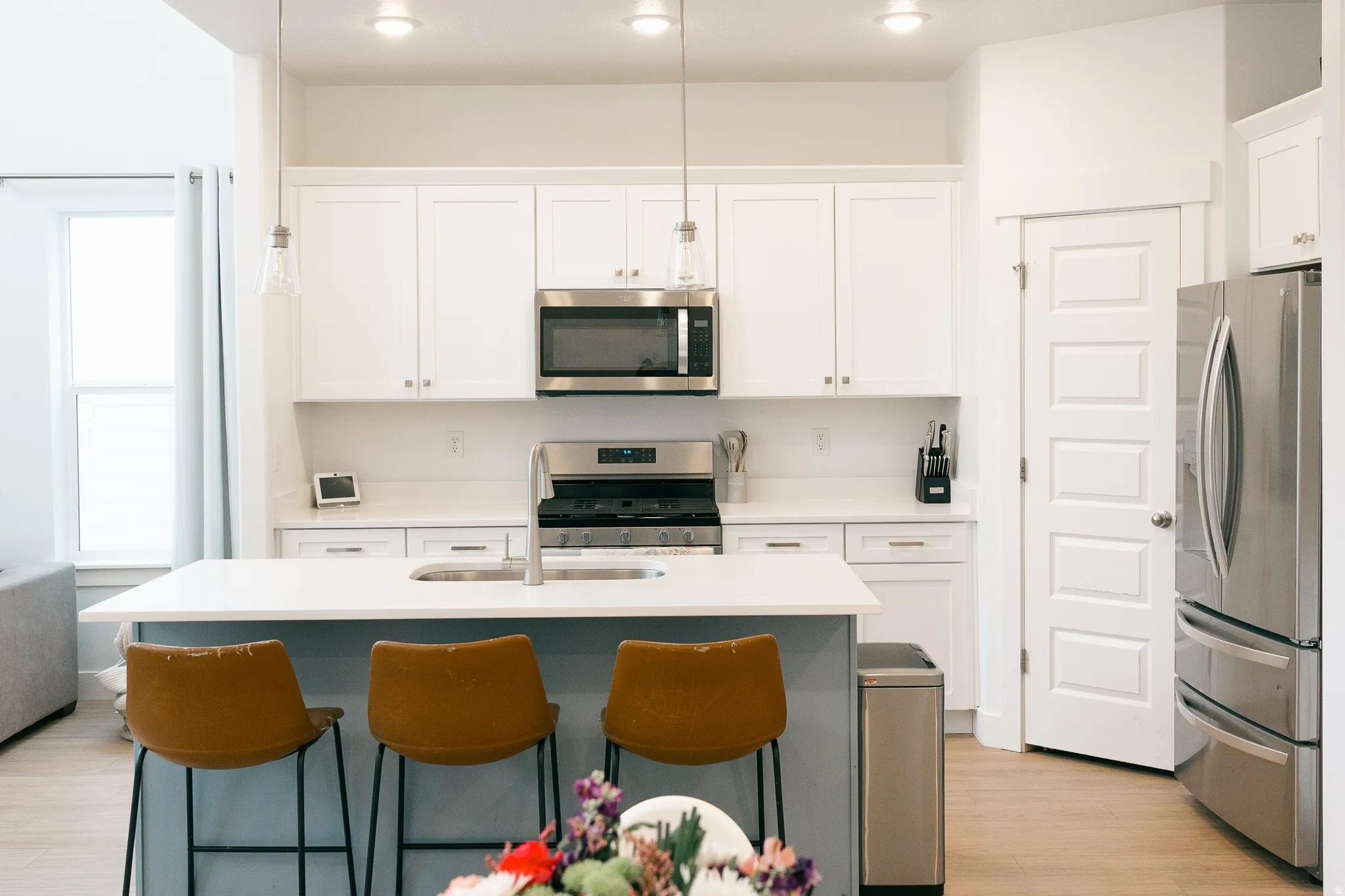 Kitchen featuring white cabinetry, stainless steel appliances, a center island with sink, light wood-finish flooring, and recessed lighting