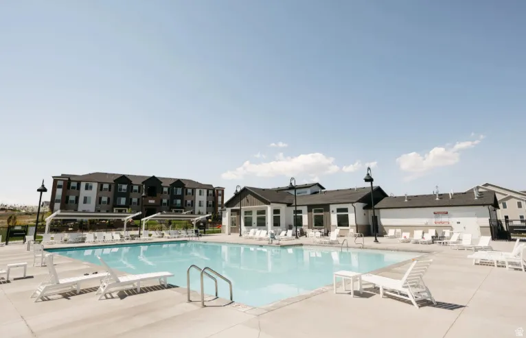 Expansive outdoor pool with integrated steps, surrounded by a concrete deck and multiple shaded lounge areas