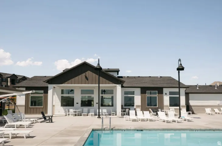 Community building with gabled roofline, concrete pool deck, and integrated swimming pool