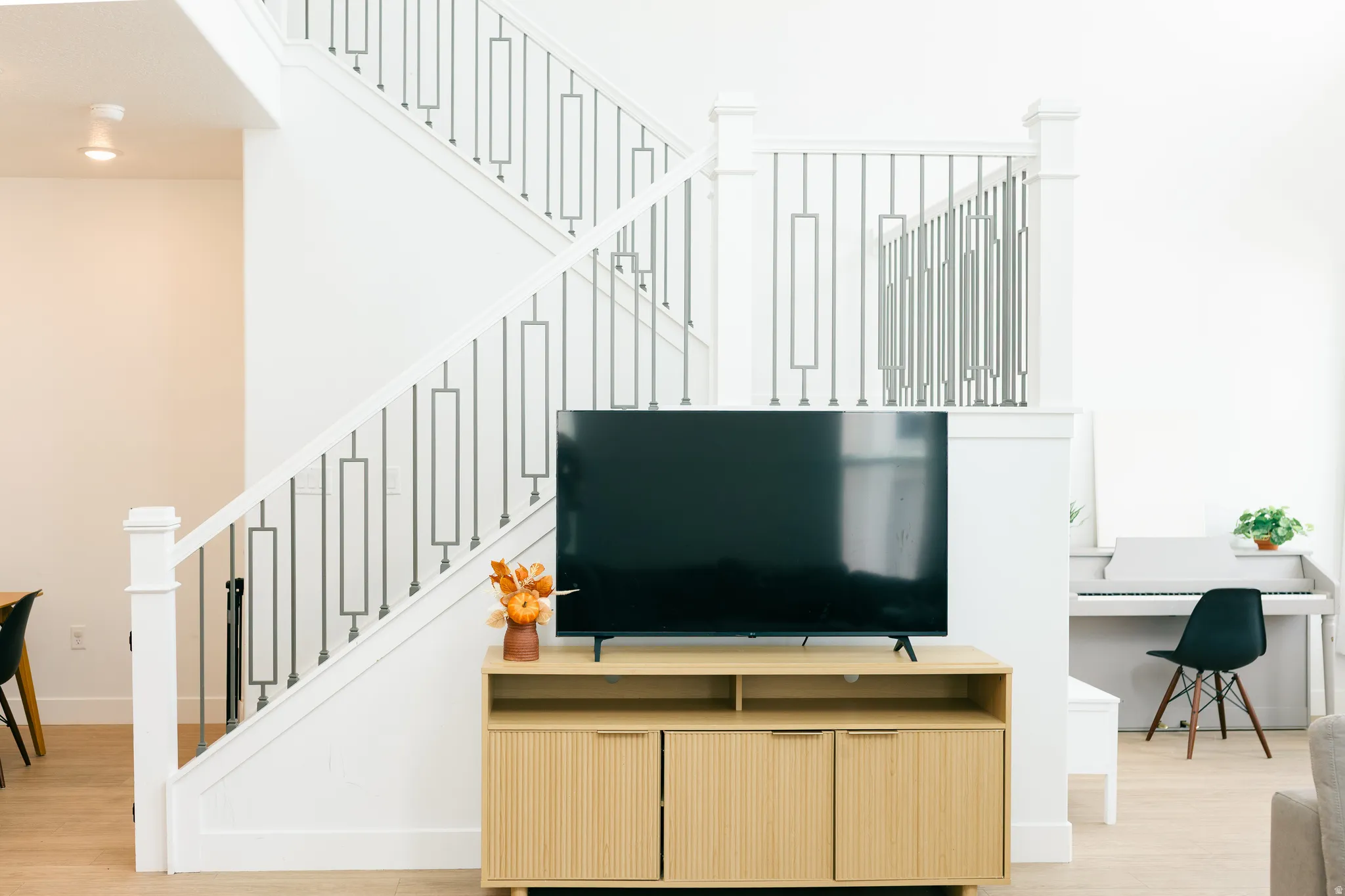 White staircase with modern metal balusters, light wood-finish flooring, and recessed ceiling lighting