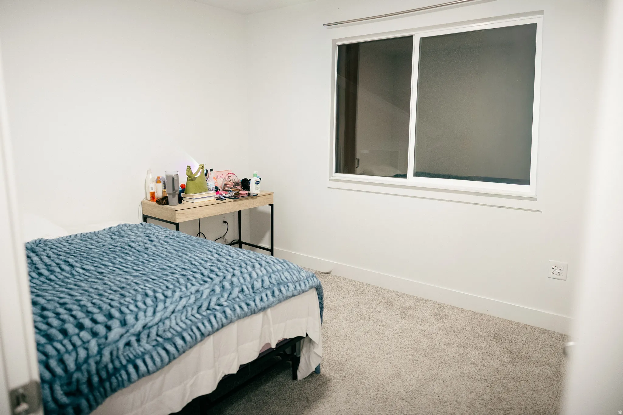Light-toned wall-to-wall carpeting, white painted walls, and a large window with white framing