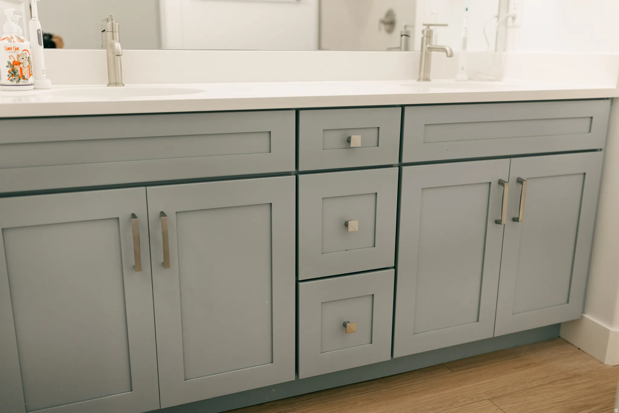 Double vanity with dual undermount sinks, single-handle faucets, and gray shaker-style cabinetry featuring varied storage options