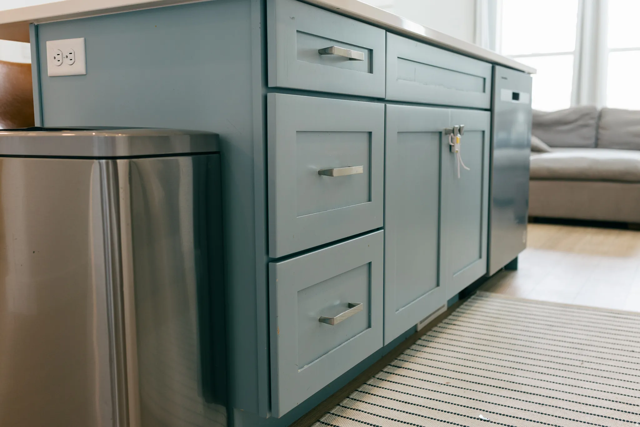 Kitchen island with light blue cabinetry, brushed nickel hardware, and built-in dishwasher