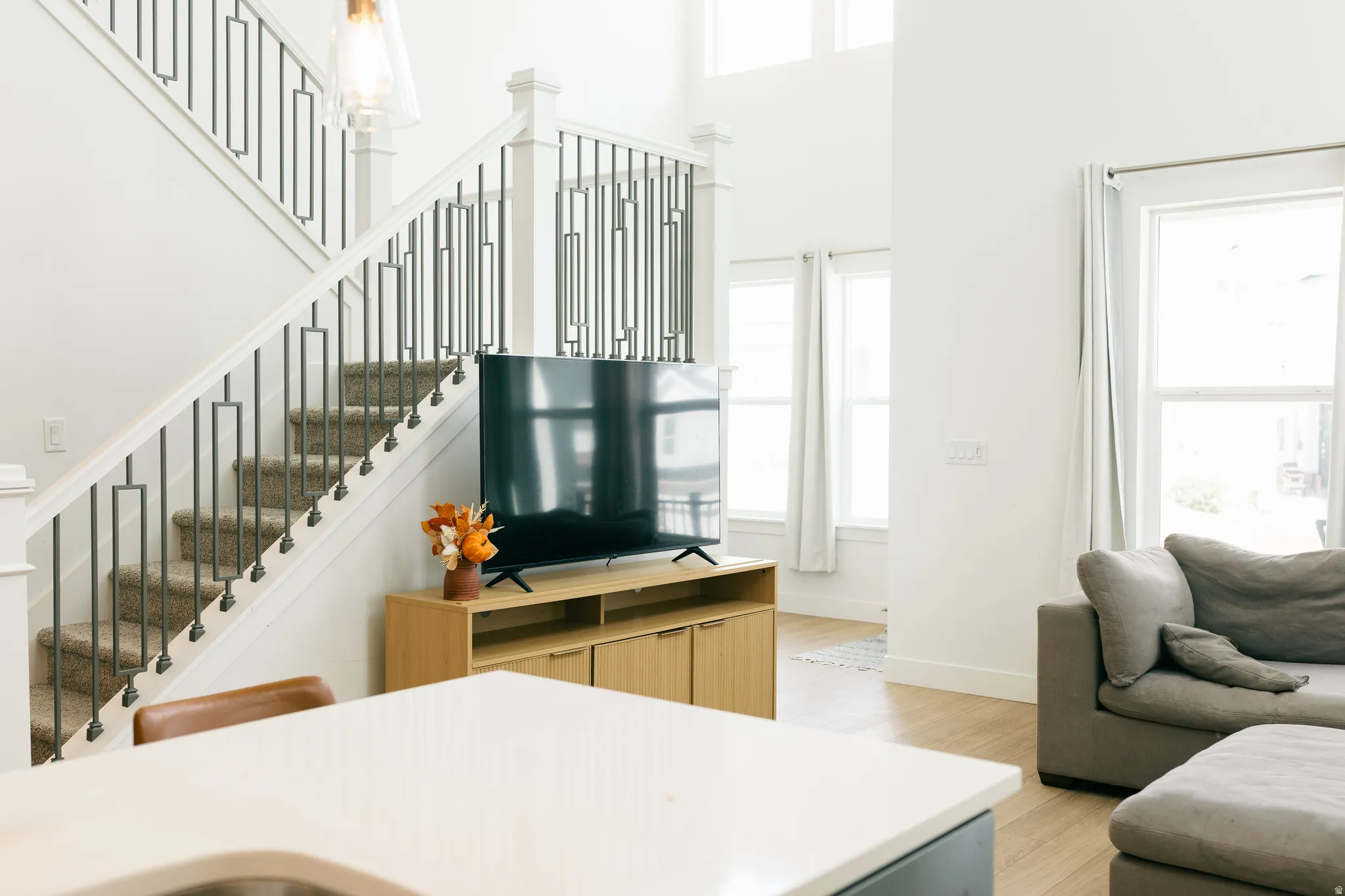 Two-story ceilings, large windows, wood-finish flooring, and a staircase with metal balusters