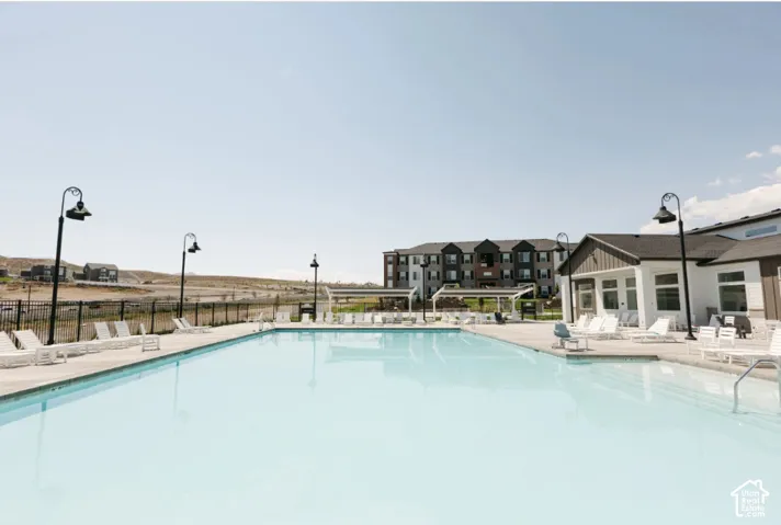 Expansive outdoor pool with integrated steps, surrounded by a concrete deck and multiple lounge chairs