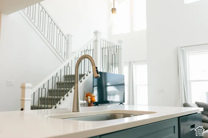 Kitchen island with a built-in sink, brushed nickel faucet, light-toned countertop, and integrated dishwasher