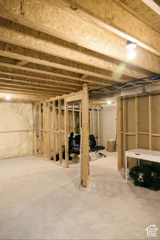Unfinished basement with exposed ceiling joists and wood stud framing